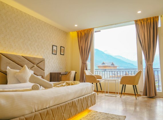 Loop Inn Manali luxurious hotel room with mountain view, modern decor, and balcony seating area.