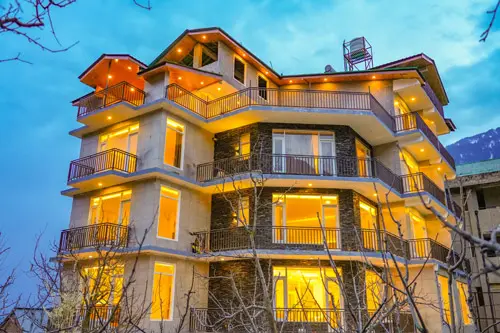 Loop Inn Manali modern multi-storey hotel building lit up in warm yellow lights at dusk in the hills